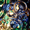 SmugMug > popular all-time > 10/13/09 - Dancing Bubbles of Light
No sun in central NC yesterday...just clouds and a light drizzle.  After I put the kids in bed last night, I experimented with my beads and glass.  This piece of glass is a small rectanguler snack tray that on one side has a raised notch were a little tea cup can sit.  I saw it at the thrift store about a week ago and thought it was really pretty to bring home.  

I've adjusted the color curves on this one in PSE.  The original colors were more pastel.  I also spent a good half an hour using the spot healing tool to remoe some tiny dots/imperfections.  The finished photo has bolder, darker colors and hopefully has a nice smooth finish.  

If you missed the details before, I take these by placing a light source over a glass object that has some sort of beads/marbles on it and shooting the picture from underneath back up through the glass.  The light shining through the beads and pattern in the glass makes the picture.  

My original plan with this was to get a 'blue' shot for the current dgrin challenge going on, but I ended up with too many colors that aren't blue.  I'll keep trying.  I need to buy a few blue beads I think.  And, I keep studying the cobalt blue glass collection that I have trying to figure out if I could do something neat with it.

There are so many great shots on the dailies each day.  I love participating in this group!

HAGD,
Maryann
